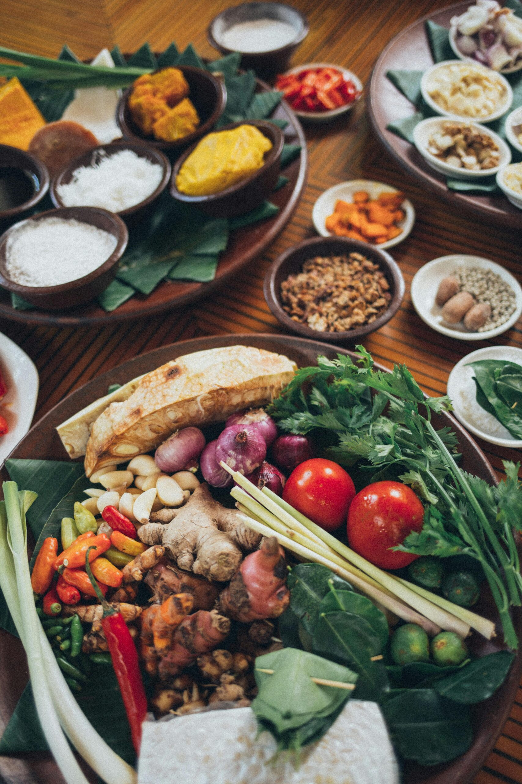 Top view of a vibrant assortment of fresh Asian vegetables and spices on a wooden table.